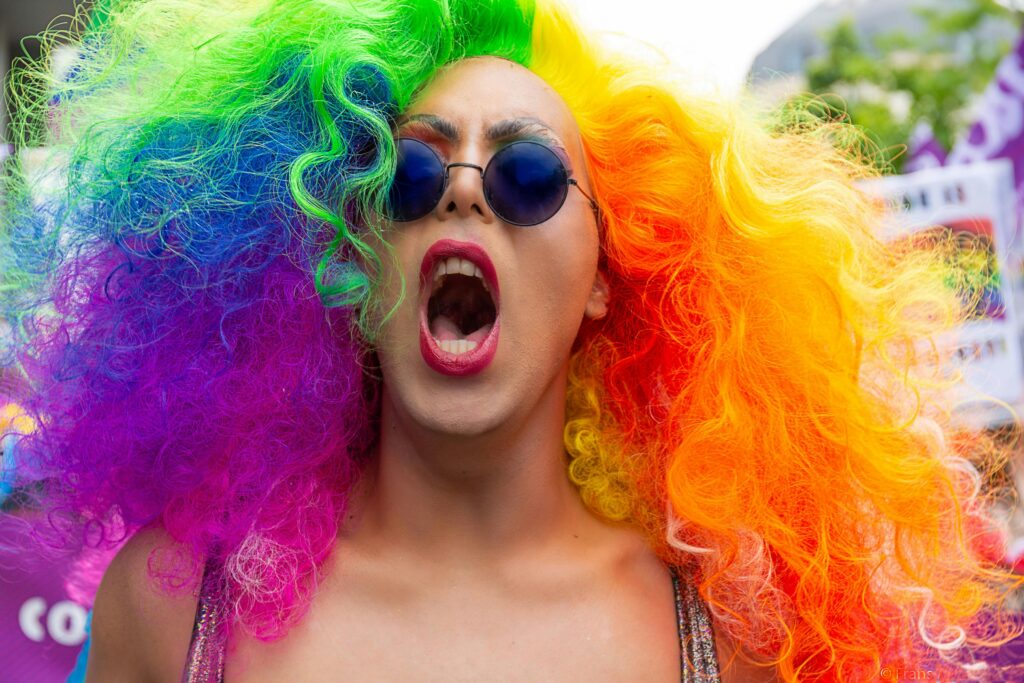 Colorful participant with rainbow wig and sunglasses at Brussels Pride Parade.