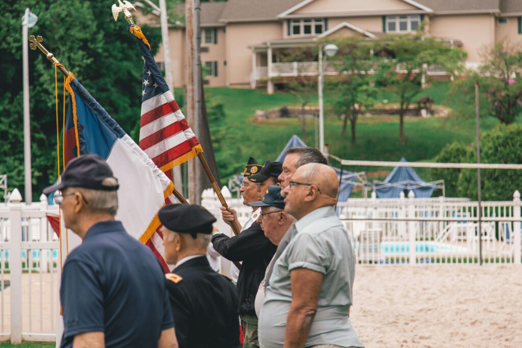 Group of veterans holding flags during an outdoor ceremony showing patriotism.