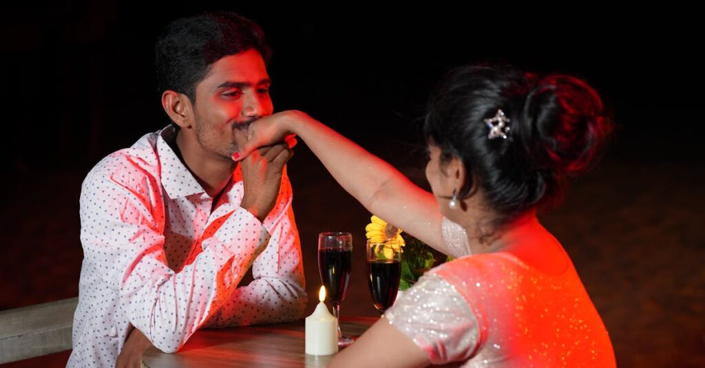 A couple enjoying a romantic candlelit dinner with wine and flowers on the beach.