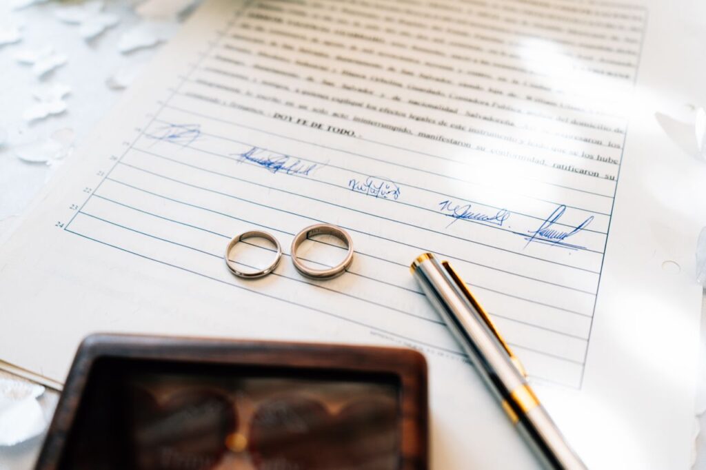 Elegant wedding rings laid on a signed marriage certificate, symbolizing commitment.