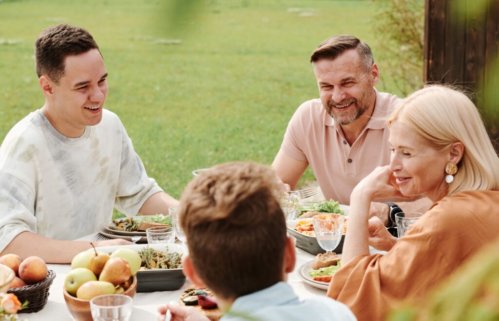 A cheerful family enjoying a meal together outdoors, sharing laughter and warmth.